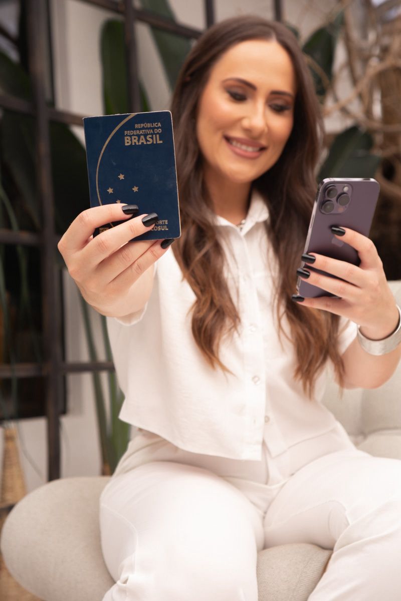 Karine segurando um passaporte e um celular